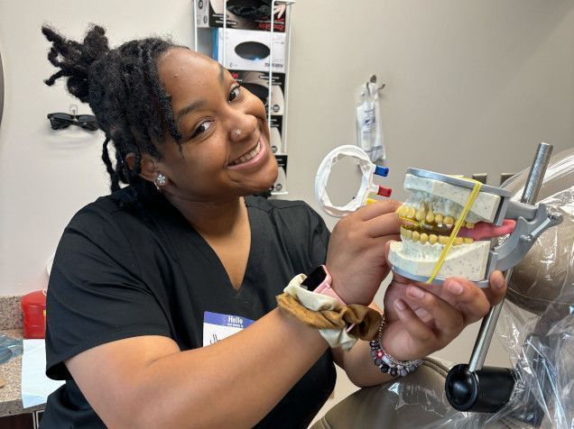 student posing with a dental mold for assistant training student posing with a dental mold for assistant training